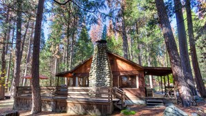 Eine rustikale Holzhütte mit einem Steinkamin, einer Holzterrasse und einer Veranda.