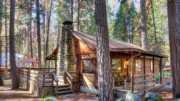 Ein rustikales Blockhaus mit Steinofen, Holzterrasse und Veranda mit Sitzgelegenheit.