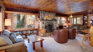 Ein gemütliches Blockhaus-Interieur mit Kamin aus Stein, Holzboden und einer komfortablen Sitzecke.