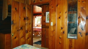 Ein Zimmer aus Holz mit einem Bett, einer Tür zu einem Essbereich und einem Fenster mit Blick.