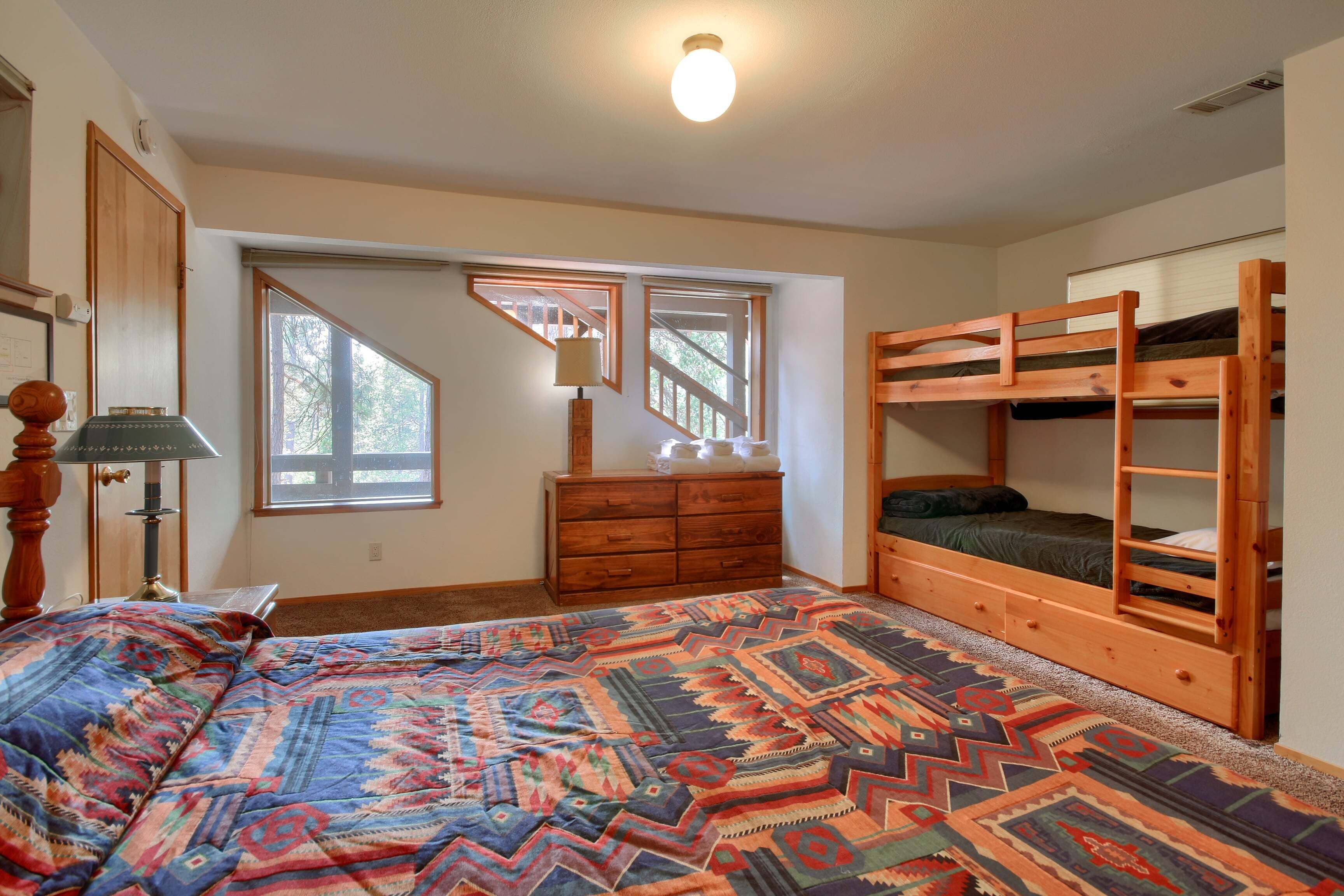 Une chambre avec un lit superposé, une commode, une lampe et une fenêtre donnant sur un beau paysage.
