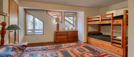 Une chambre avec un lit superposé, une commode, une lampe et une fenêtre donnant sur un beau paysage.