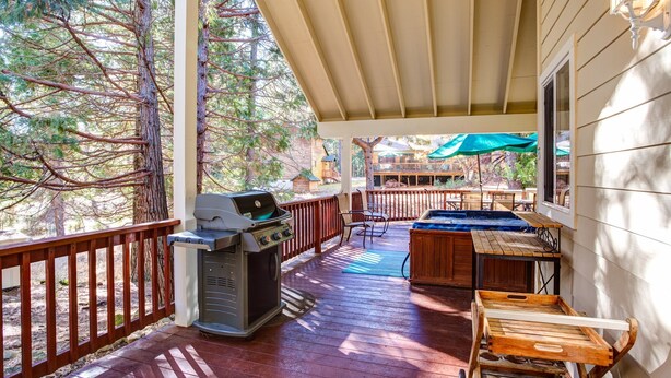 Una terrazza esterna coperta con barbecue, vasca idromassaggio e mobili in legno.