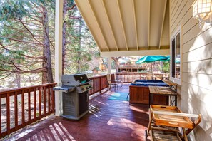 Eine überdachte Terrasse im Freien mit Grill, Whirlpool und Holzmöbeln.