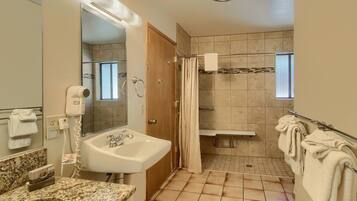 A bathroom with a sink, mirror, towel rack, shower, and a window.