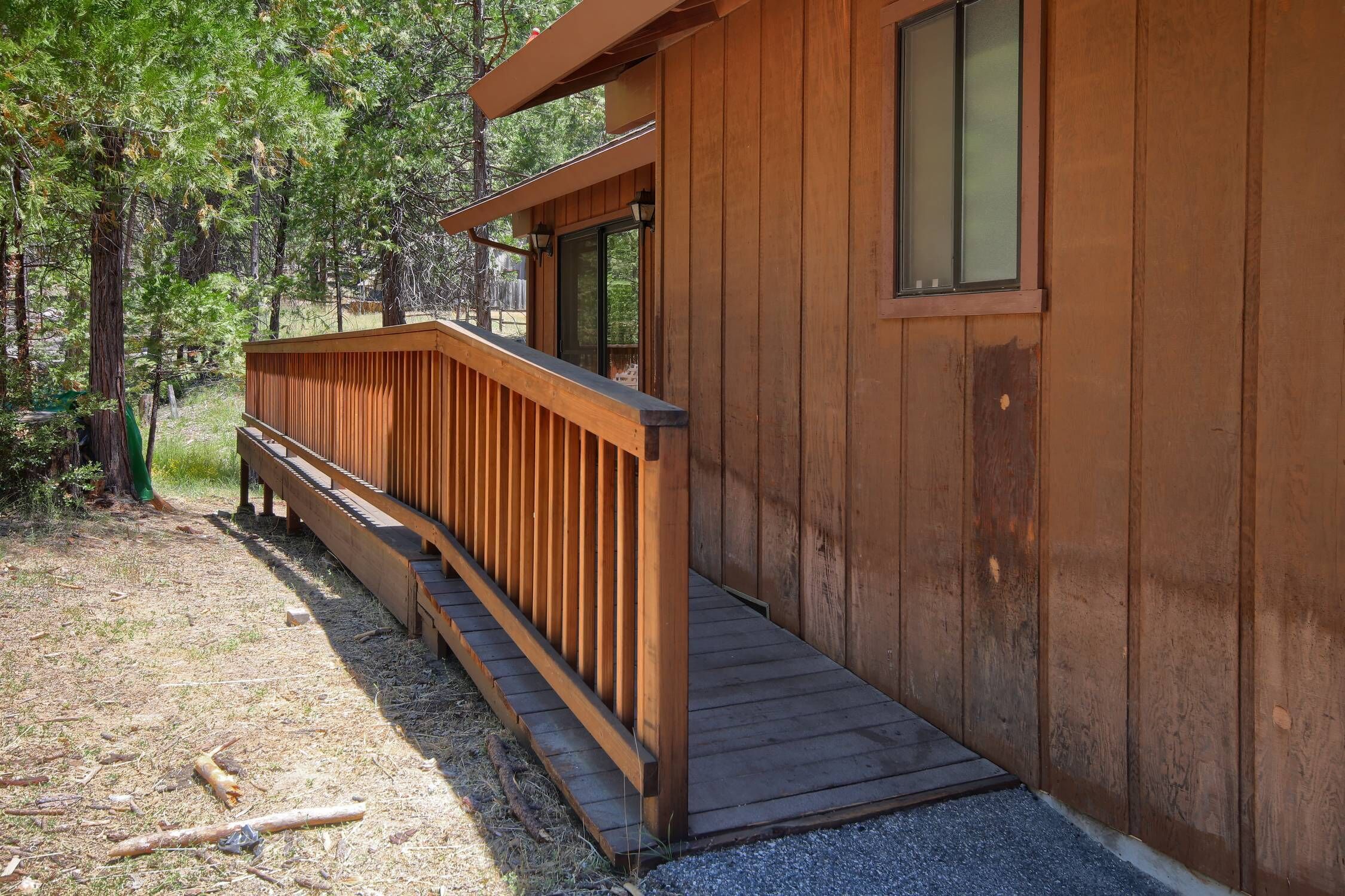 A wooden cabin with a wooden deck and a small porch.