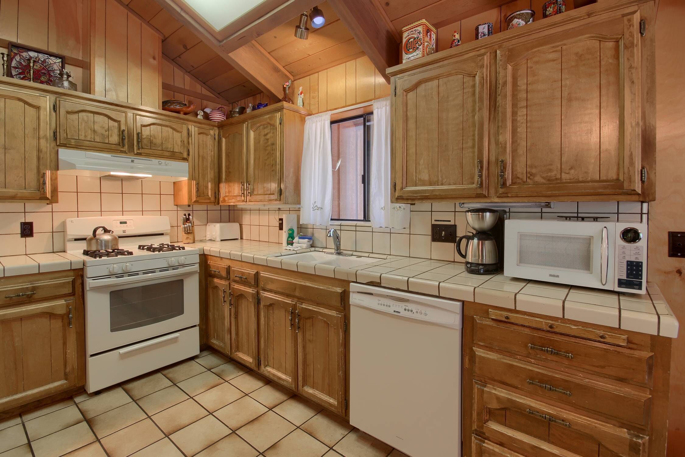A kitchen with wooden cabinets, a stove, a dishwasher, and a microwave.