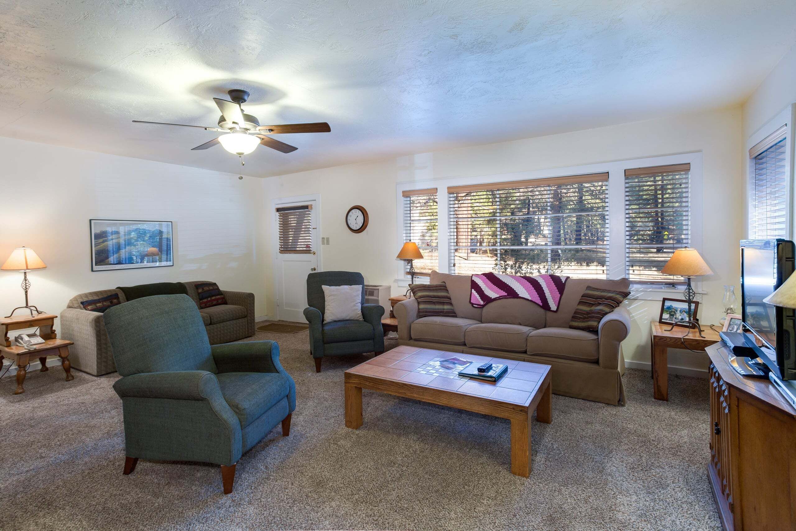 A living room with a ceiling fan, two couches, a coffee table, lamps, and a TV.