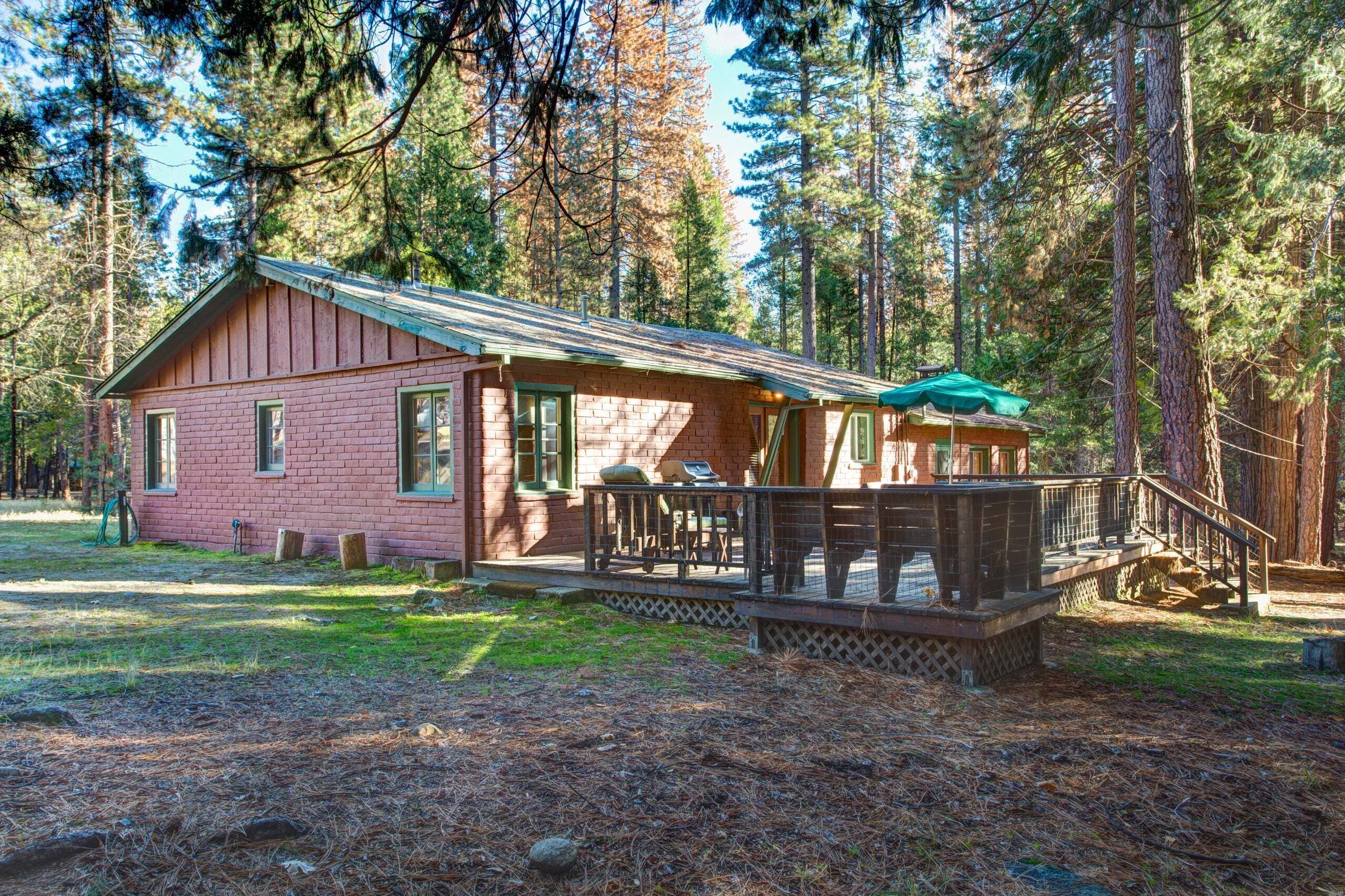 A cabin with a deck, surrounded by trees.