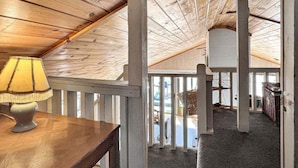Un interno in legno con soffitto alto, una lampada su un tavolo e una vista attraverso una finestra.