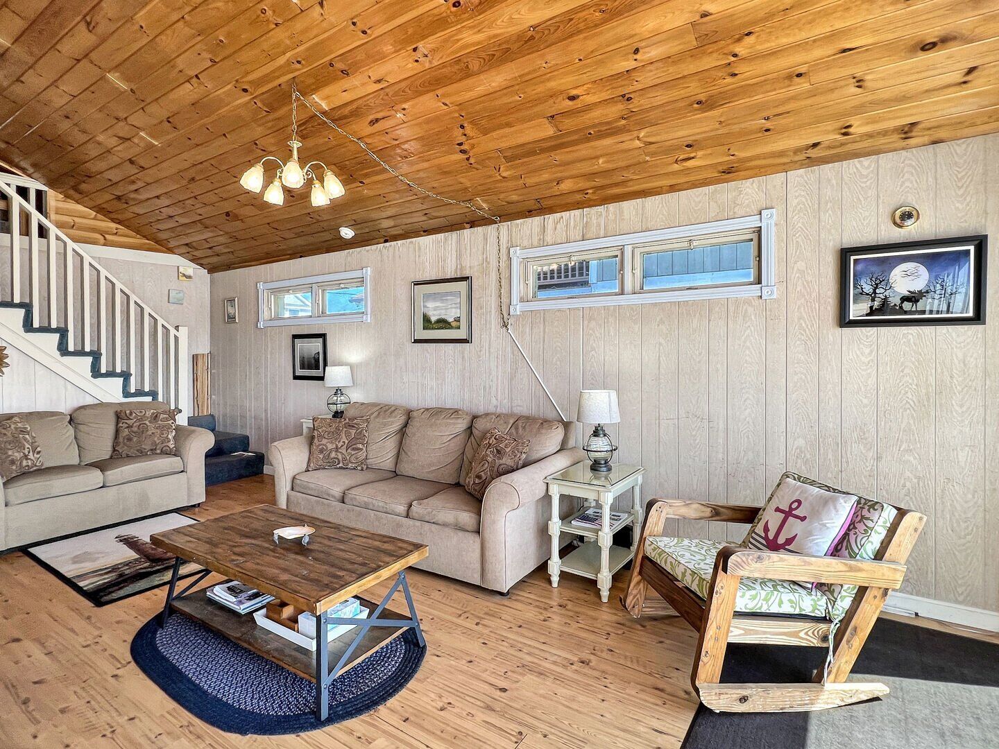 A cozy living room with a wooden ceiling, a sofa set, a coffee table, and a rocking chair.