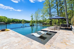 A swimming pool with lounge chairs and a pergola, surrounded by trees and a view of a lake. - Fox Run LKN (Denver)
