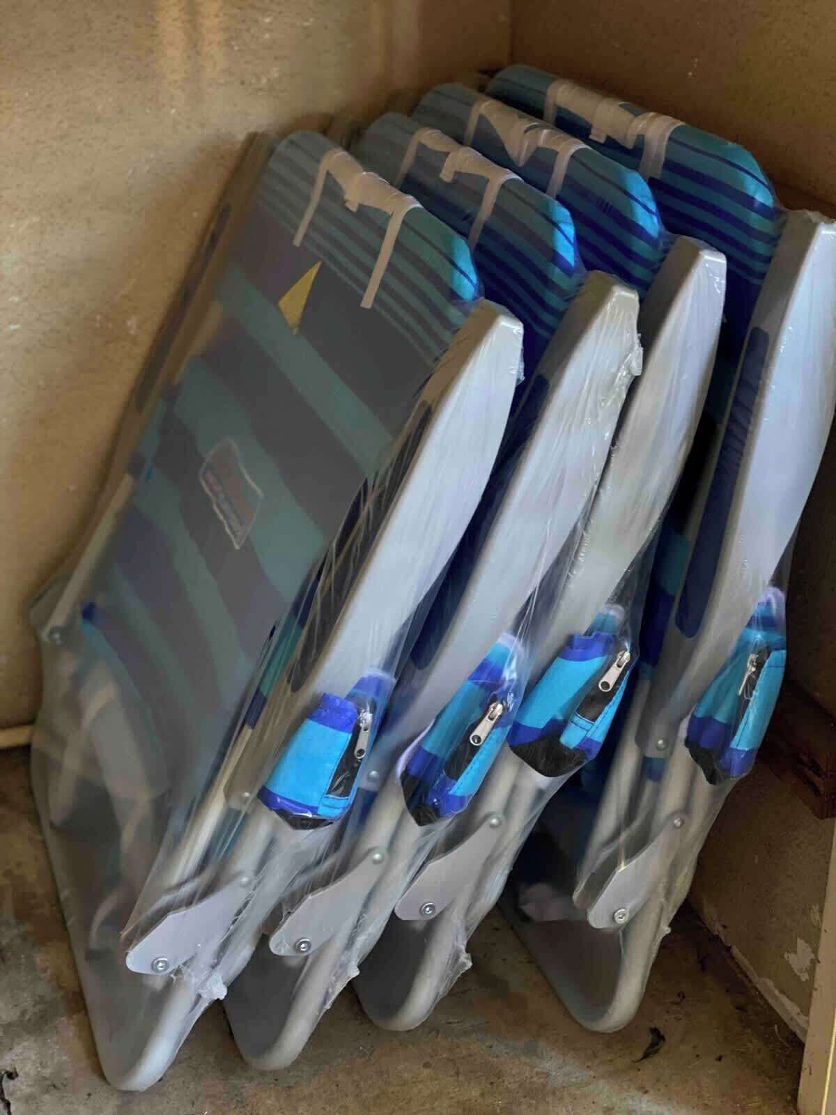 Ein Stapel grauer und blauer Reisetaschen mit Rollen, teilweise in Plastik eingeschlagen.