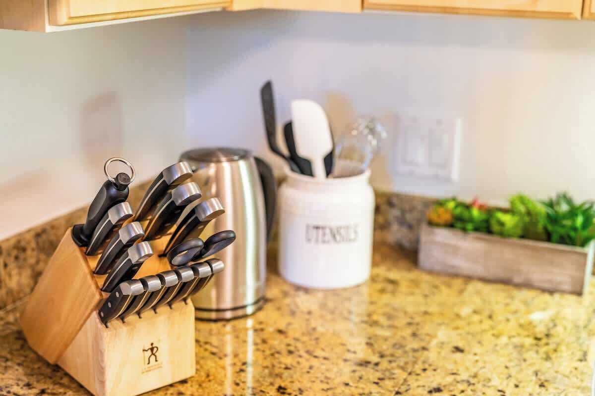 Un piano di lavoro in cucina con un portachiodi, un bollitore in acciaio inossidabile e un portautensili.