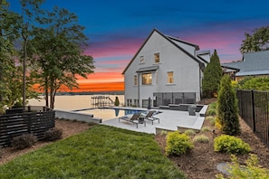 Una casa moderna con piscina, terrazza e vista sul tramonto sull'acqua.