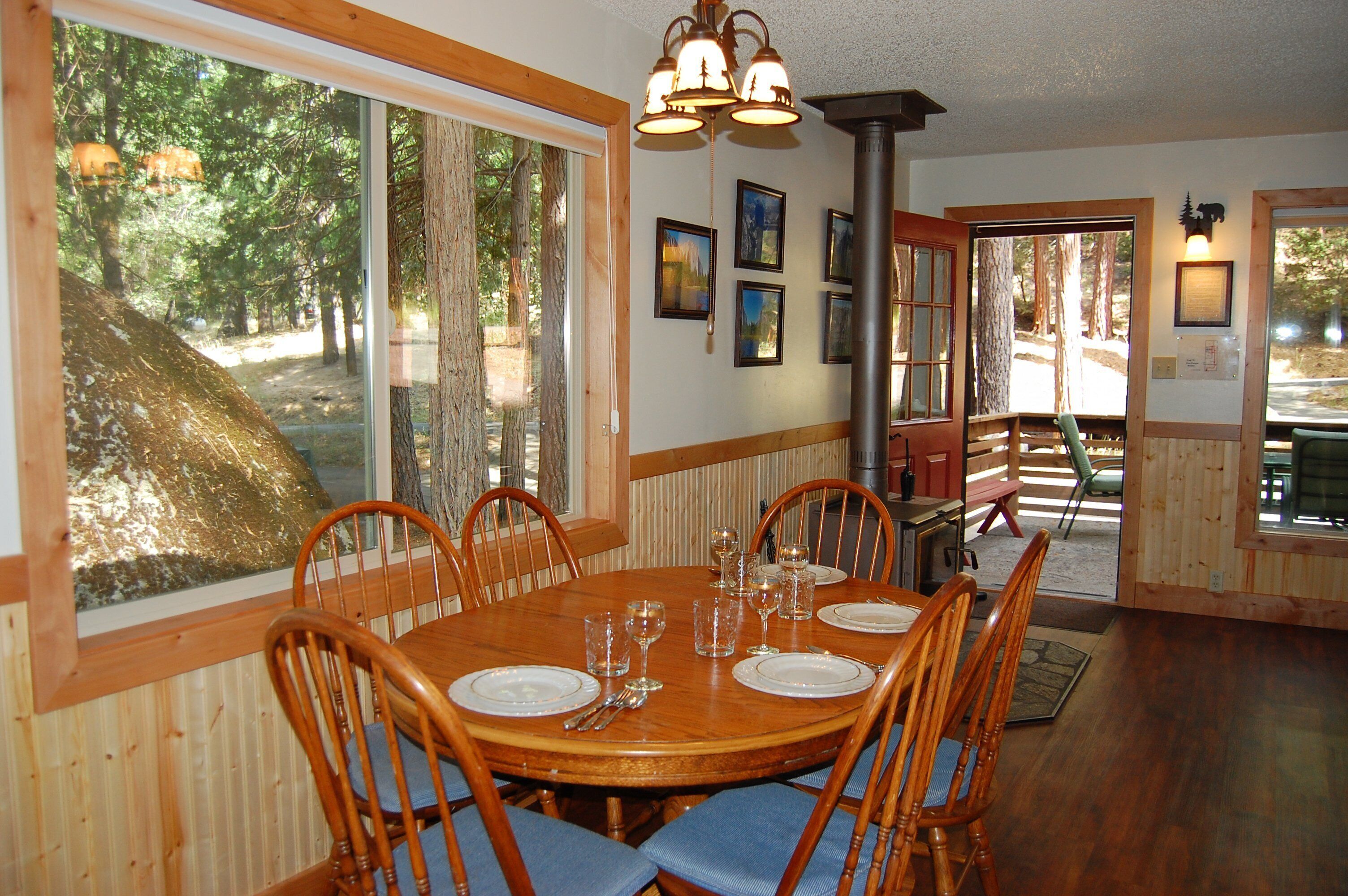 A dining area with a wooden table set for six, surrounded by chairs.