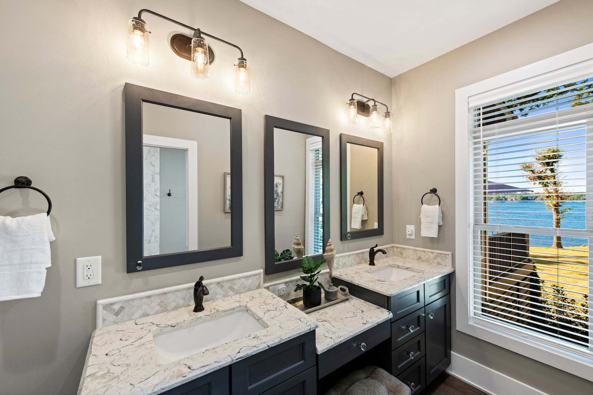 A bathroom with two sinks, a large mirror, and a window with blinds.
