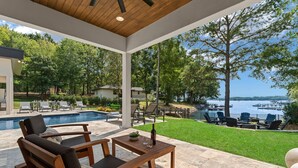A covered patio with a pool, outdoor seating, and a view of a lake. - Shoreline on Stonemarker (Mooresville)