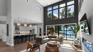 A spacious living area with a large sofa, wooden chairs, a coffee table, and a view of a pool. - Shoreline on Stonemarker (Mooresville)