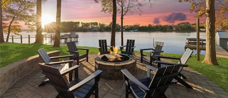 A lakeside patio with 14 beds and 18 sleeps, surrounded by trees and a fire pit.