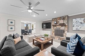 A modern living room with a fireplace, grey sofas, and a ceiling fan. - Hillstone Ridge (Mooresville)