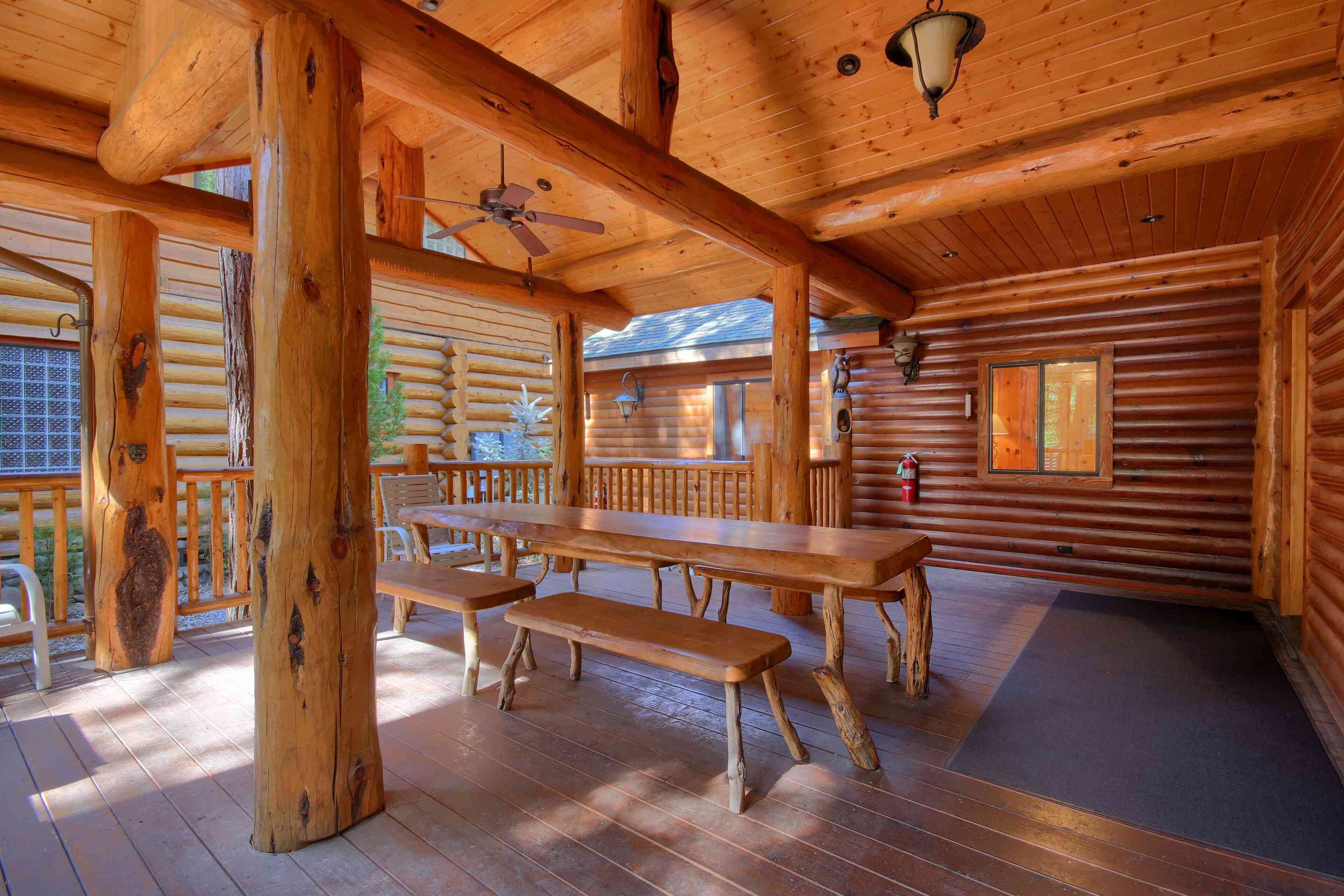 Una baita di legno con una terrazza, un ventilatore a soffitto e un grande tavolo da pranzo con panche.