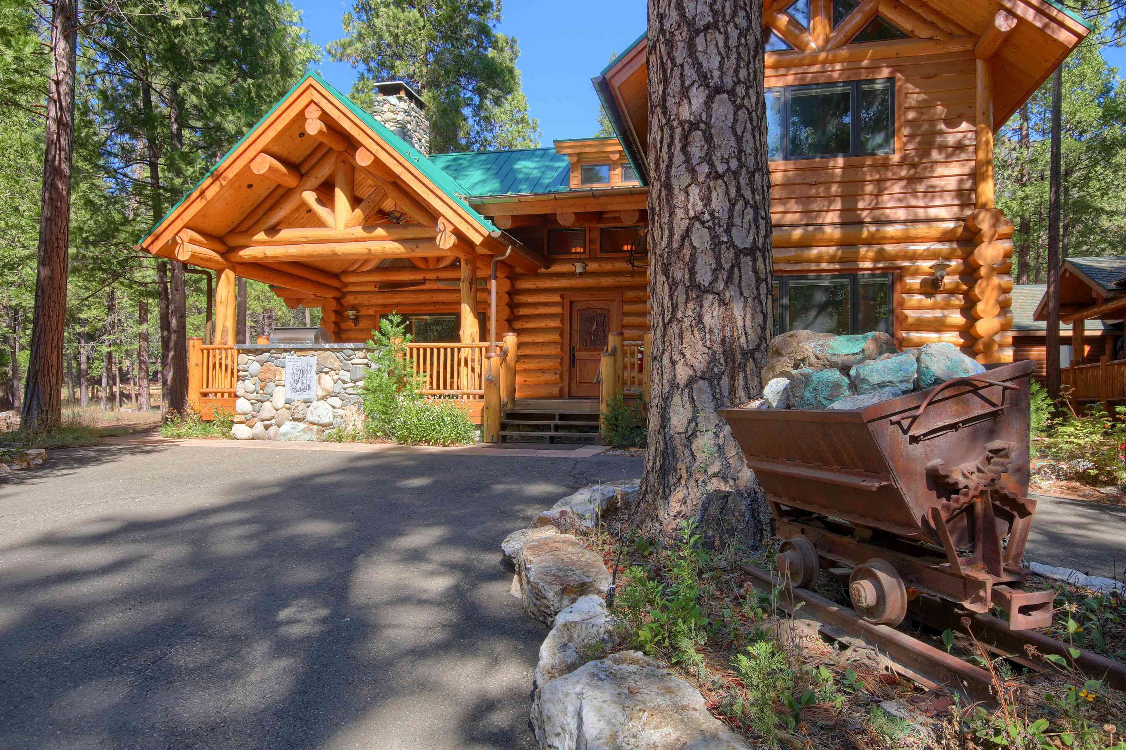 Une cabane en rondins avec un porche, des fondations en pierre et un vieux tracteur.