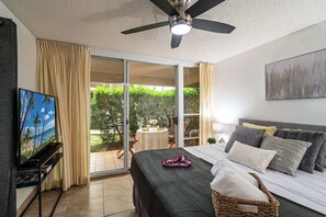 Une chambre à coucher avec un lit, un ventilateur de plafond, une télévision et une vue sur l’extérieur.