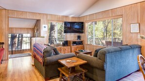 A cozy living room with a sofa, a coffee table, and a TV mounted on the wall. - Yosemite's Riverfront Retreat (Yosemite National Park)