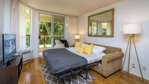 Ein Hotelzimmer mit Bett, Sofa, Fernseher, Lampe und einem großen Fenster.