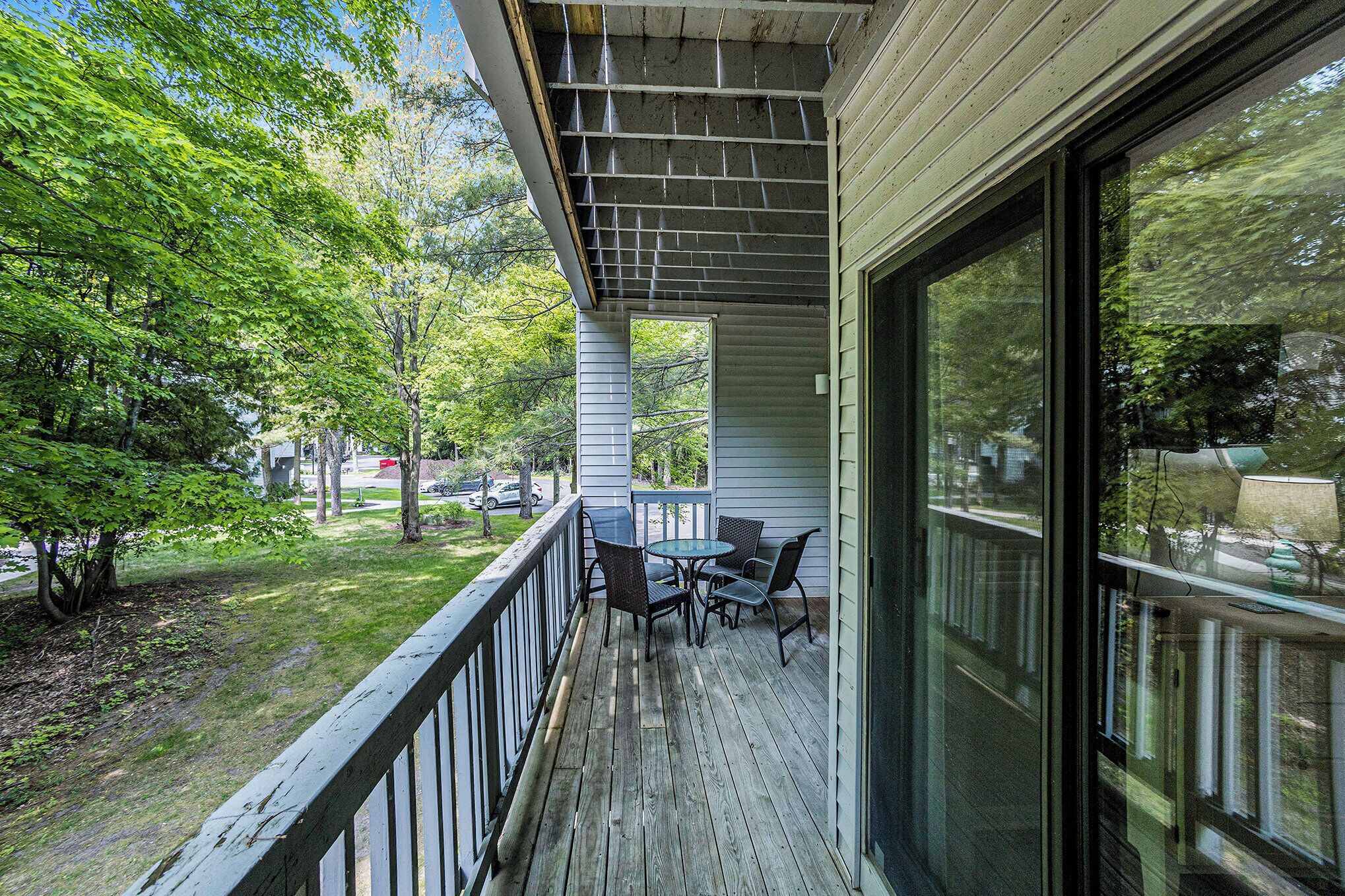 A wooden deck with a table and chairs, surrounded by trees.