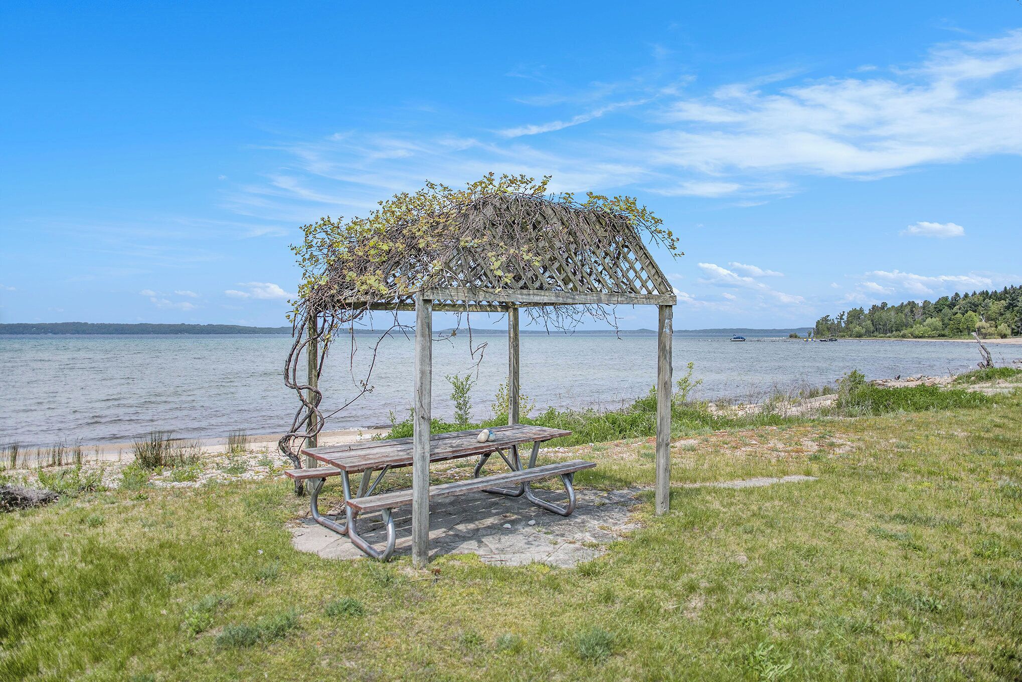 A wooden gazebo with benches by a lake.