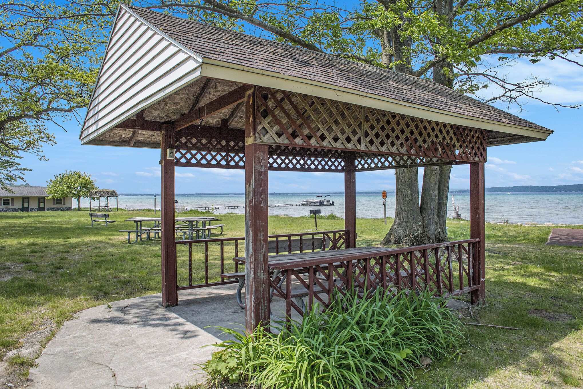 Ein Gazebo mit Gitterdach und hölzernen Bänken in der Nähe von Wasser.