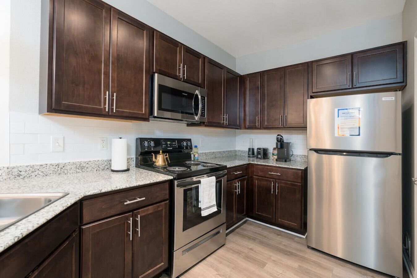 A modern kitchen with dark wood cabinets, stainless steel appliances, and a granite countertop.