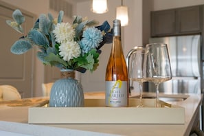 A tray with a bottle of Light Hearted Rose wine, two glasses, and a vase with flowers. - Luxurious One Bedroom Whitestown (Whitestown)