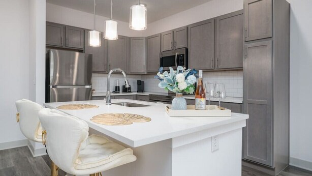 A modern kitchen with a central island, stainless steel appliances, and pendant lighting. - Luxurious One Bedroom Whitestown (Whitestown)