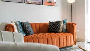 A modern living room with a sofa, decorative pillows, and abstract art on the wall. - Luxurious One Bedroom Whitestown (Whitestown)