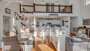 A spacious open-plan living area with a dining table, wicker chairs, a sofa, and a kitchen in the background. - Eagle Roost Chalet- Modern Kentucky Lake Chalet (Waverly)
