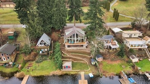 A lakeside property with a main house, a dock, and a boat. - Lakefront Escape Fire Pit, Pets & Amazing Views (Stanwood)