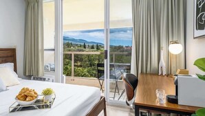 Quarto de hotel com cama, mesa de jantar, cadeira, luminária e vista para o exterior.