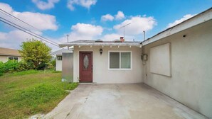 A single-story house with a front door, a small window, and a garage door. - Marbella Lane - Your Cozy Haven 2BR Retreat (West Covina)