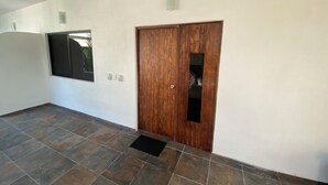 A hallway with a wooden door, a window, and a ceiling fan. - Costa Ayala suite 8 with 2 dbl bed and 1 sofa, all basics, 2 blocks from beach (Los Ayala)