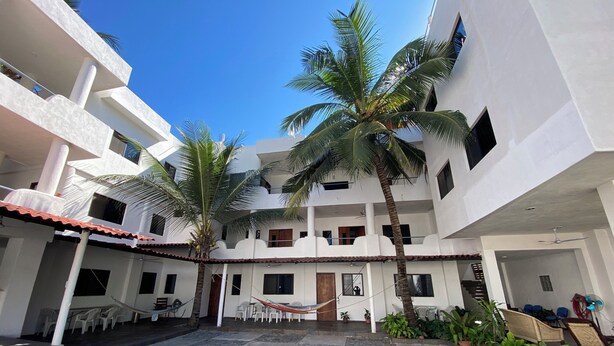 A courtyard with a tiled floor, white buildings, palm trees, and outdoor seating. - Costa Ayala suite 8 with 2 dbl bed and 1 sofa, all basics, 2 blocks from beach (Los Ayala)