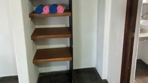 A corner of a room with a wooden shelf unit against a white wall, containing rolled-up items. - Costa Ayala suite 8 with 2 dbl bed and 1 sofa, all basics, 2 blocks from beach (Los Ayala)