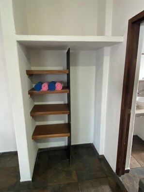Ein Teil eines Raumes mit einer Holzregaleinheit an einer weißen Wand, mit eingerollten Gegenständen.