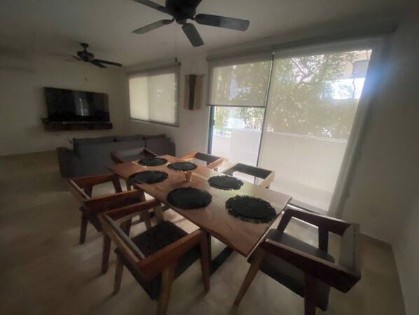 A dining area with a wooden table, six chairs, and a ceiling fan. - Beautiful 2 Bedrooms in Parques Zama Torre 2 (Tulum)