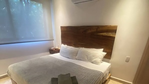 Ein modernes Schlafzimmer mit einem großen Bett, einem Deckenventilator, einer Klimaanlage und einem Fenster mit Blick auf Bäume.
