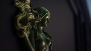 Un gros plan d’une sculpture en bronze sur une surface sombre.