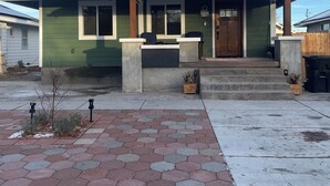 A single-story house with a green exterior, a metal roof, and a front porch with steps. - The Quilting House a charming craftsman home centrally located in Burley (Burley)