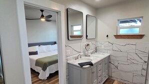 A modern bathroom with a marble backsplash, a double sink vanity, and a ceiling fan. - The Quilting House a charming craftsman home centrally located in Burley (Burley)